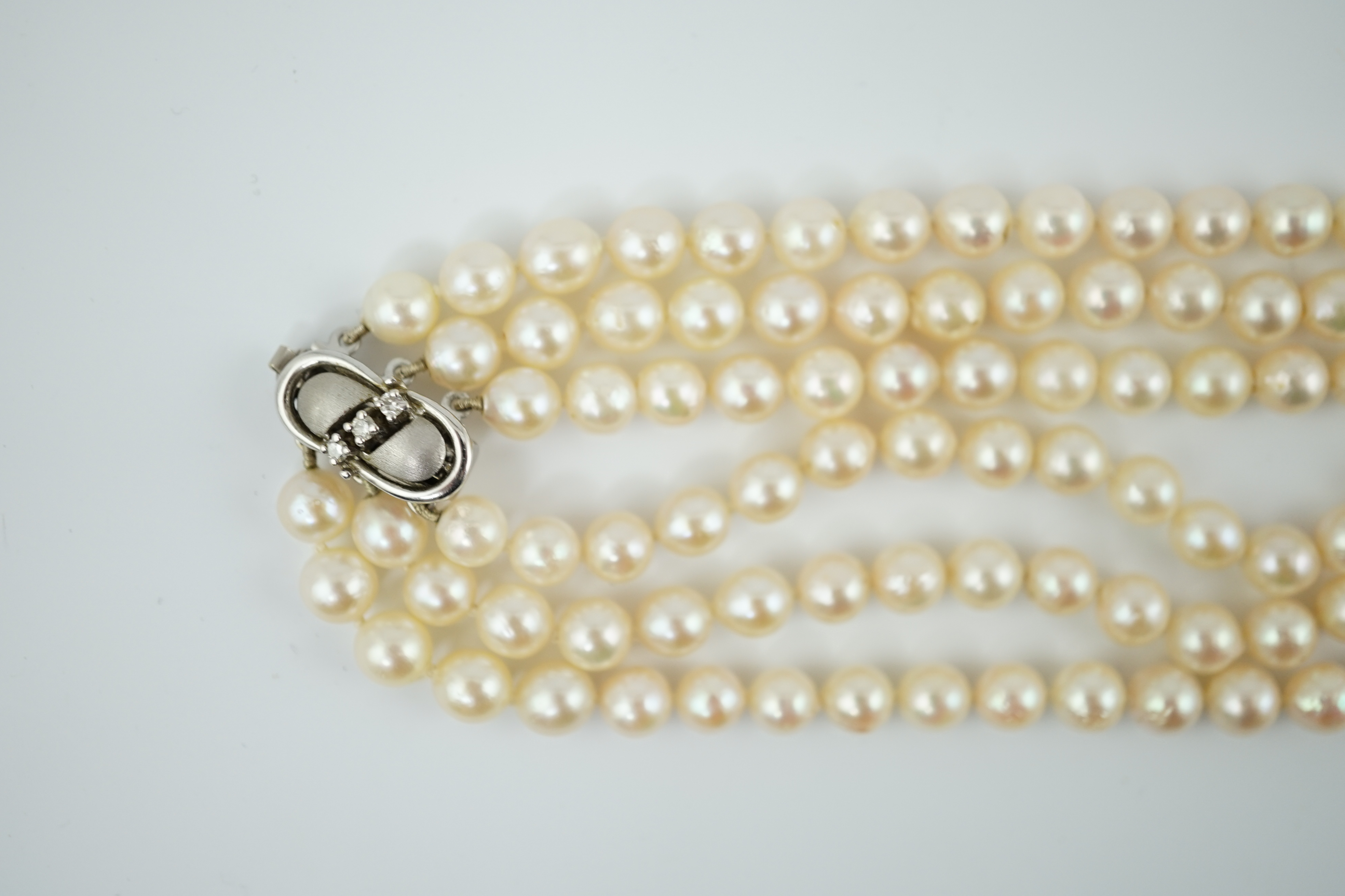 A modern triple strand cultured pearl choker necklace, with three stone diamond set 14k white gold clasp